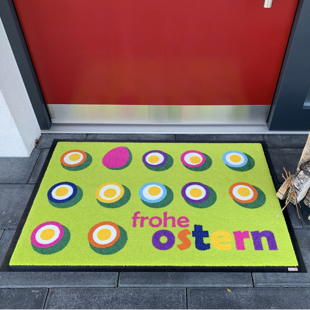 Grüne Fußmatte mit bunten Akzenten liegt vor einer Tür